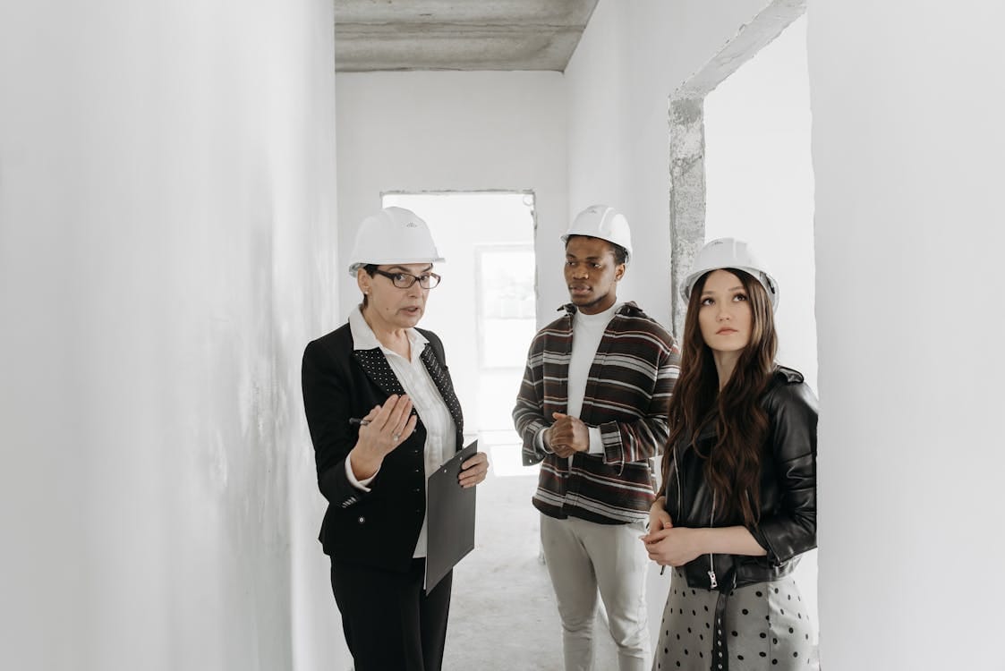 real estate agent and a young couple in helmets having a conversation