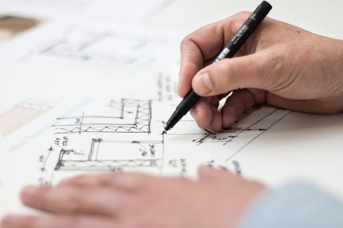 close-up of a person using a black pen drawing on a floor plan