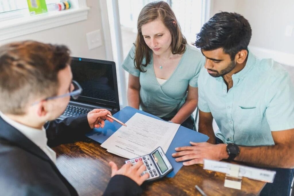 a couple sitting across a realtor at his office going through property papers