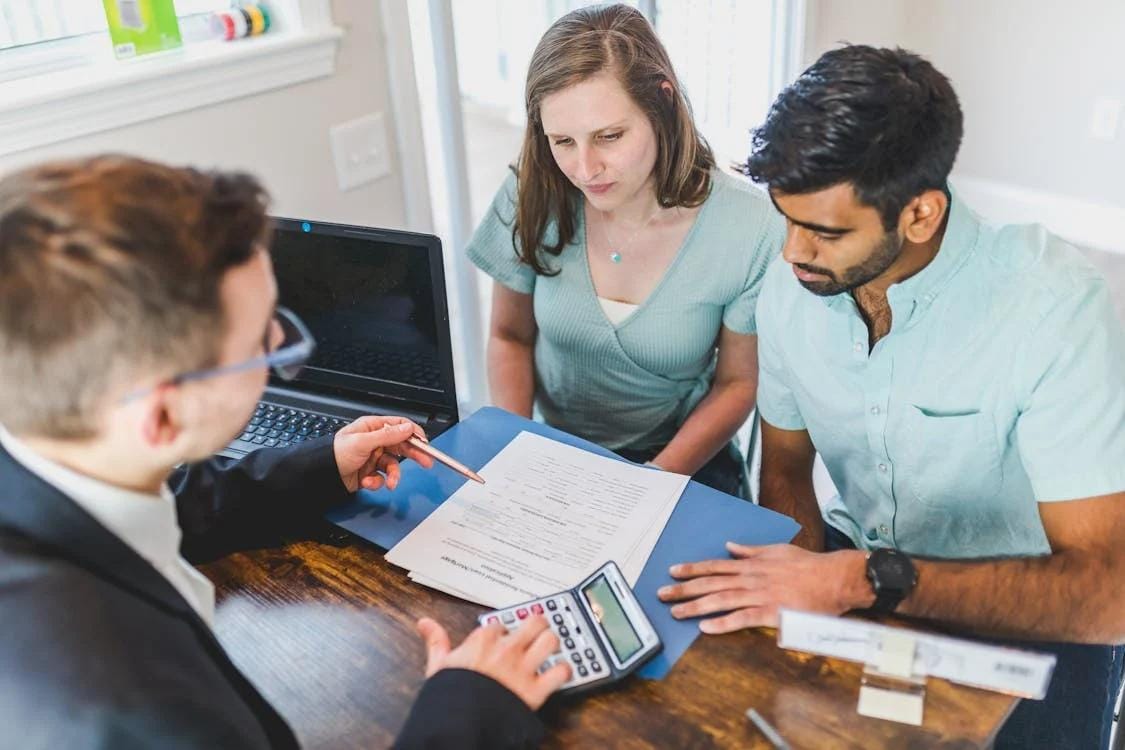 a couple sitting across a realtor at his office going through property papers