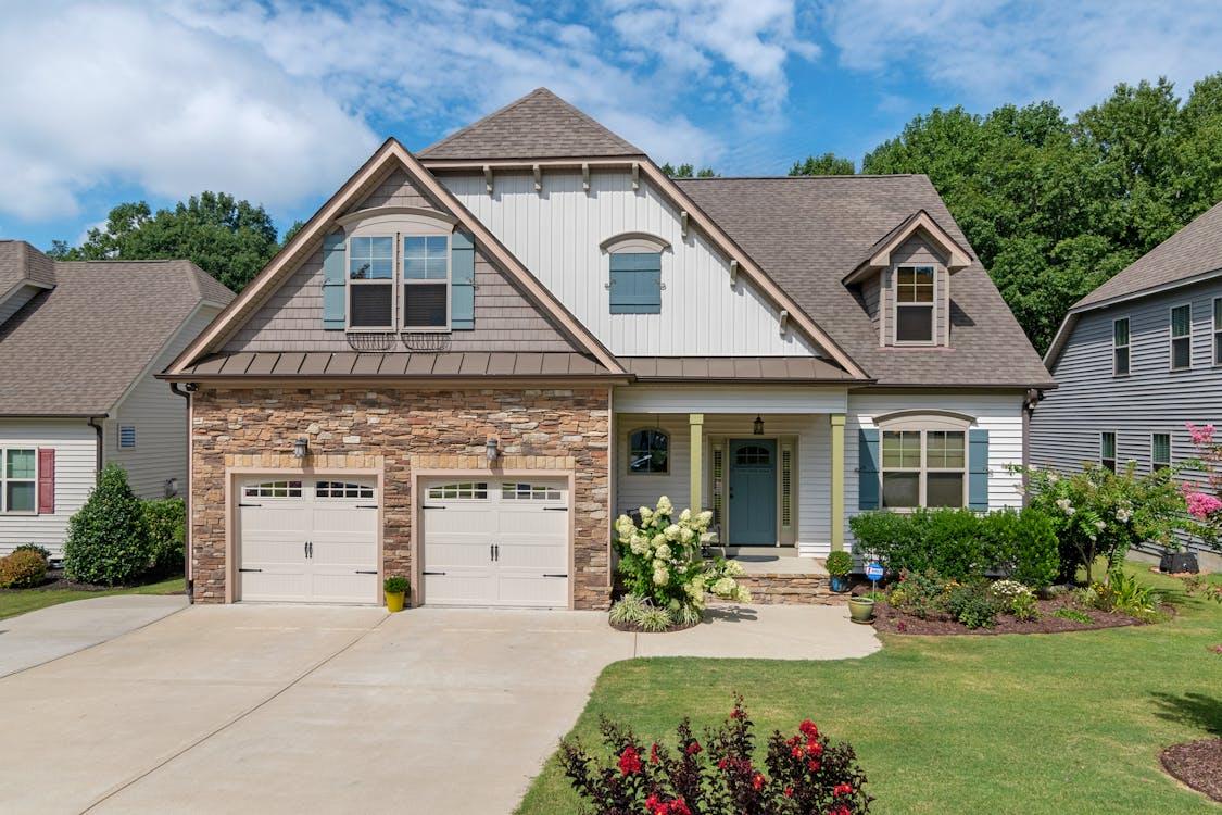 Two-story modular home with stone accents, double garage, and manicured yard.